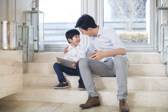 Cheerful father and son using electronic products in the living room