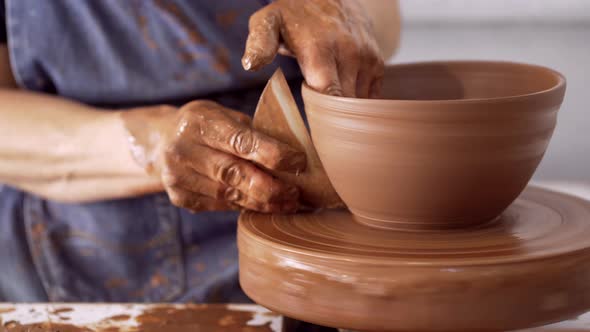 Man at pottery wheel making clay bowl