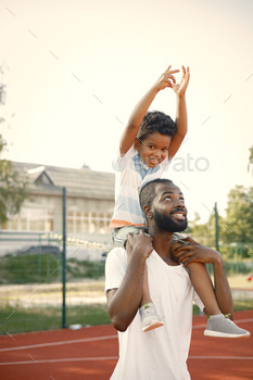 Young black father holding on shoulders his little multiracional son