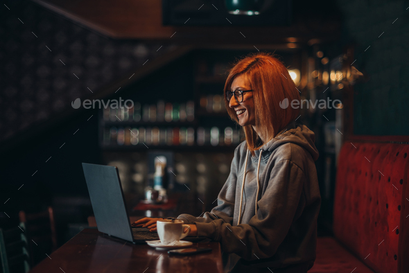 Busy redhead woman working on her laptop in a cafe - Stock Photo - Images