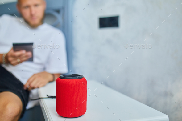 Male testing talking smart wireless speaker, man controlling home devices with a voice commands