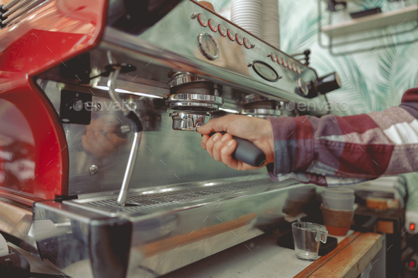 Man barista wearing in plaid shirt holding filter with pressed coffee