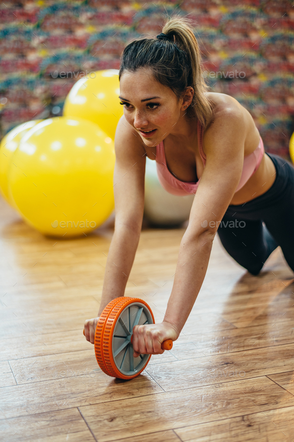Woman training with ab wheel rollouts in the gym