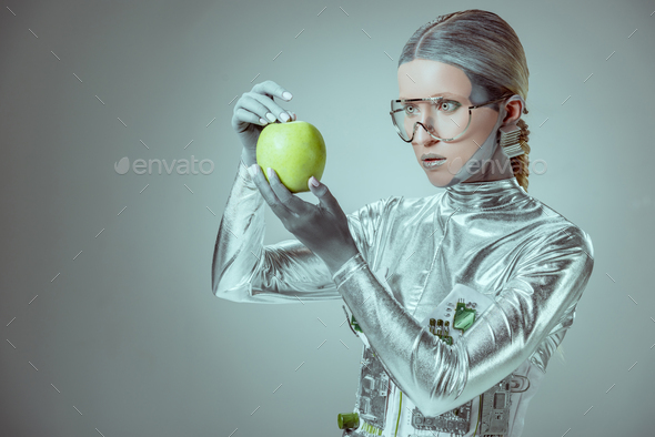 robot in futuristic eyeglasses holding green apple isolated on grey, future technology concept