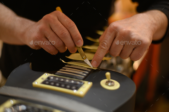 Guitar in repair service shop with a hands of a guitar luthier which fixes it