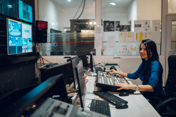 Middle aged woman working on a tv station as a producer in a broadcast control room