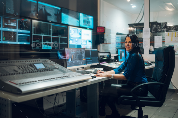 Middle aged woman using equipment in control room on a tv station - Stock Photo - Images