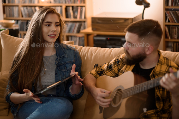 Couple hanging at home while playing guitar and listening vinyl records