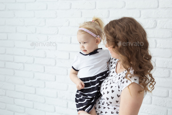 Mother holds her deaf child with hearing aids and cochlear implants - Stock Photo - Images