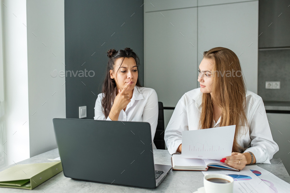 Two female colleagues communicate in office at work. Work place. Use technology and Internet.