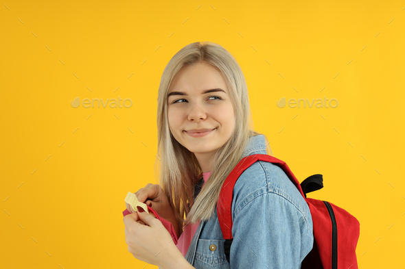 Student girl with cheat sheet on yellow background