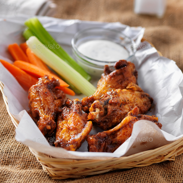 bbq buffalo chicken wings in basket, with ranch dip, carrot and celery sticks