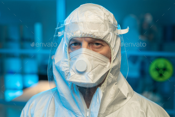 Face of male researcher in biohazard suit, respirator and protective screen