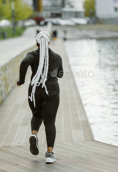 Afro-american plus size woman jogging outdoor
