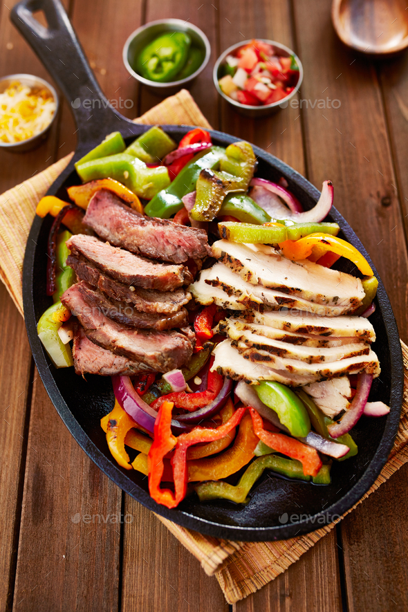 chicken and steak mexican fajitas in iron skillet Stock Photo by joshua_resnick