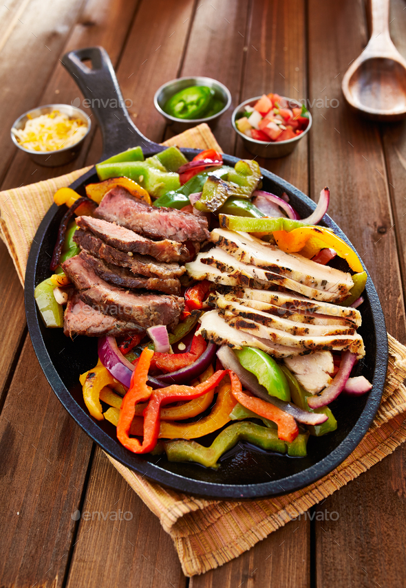 chicken and steak mexican fajitas in iron skillet Stock Photo by joshua_resnick