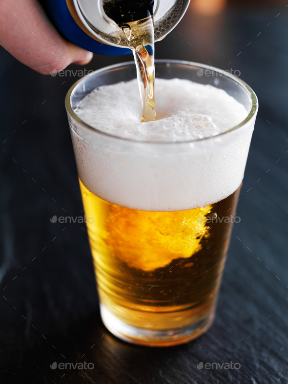 filling up a glass with beer from can