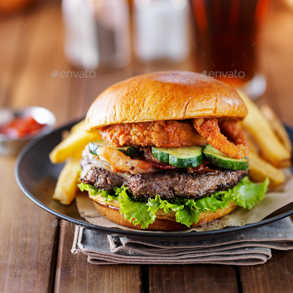 big burger close up with onion ring topping and bacon Stock Photo by