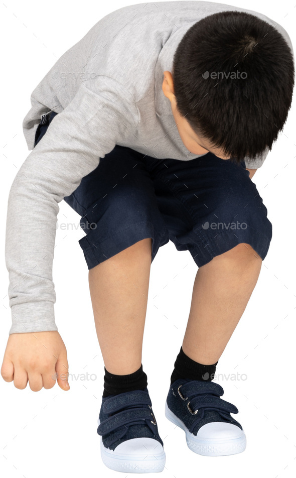a young boy wearing blue shorts and a gray shirt is kneeling down