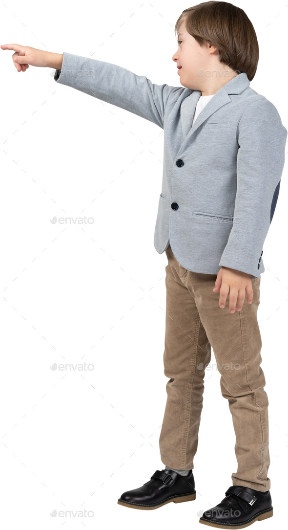 a young boy in a blue jacket and brown pants pointing at something