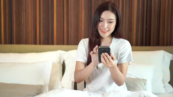 woman using her smartphone on bed alt