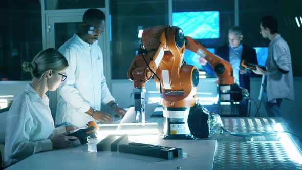 Robotic Laboratory with a Group of Researchers Working with Industrial Robots alt