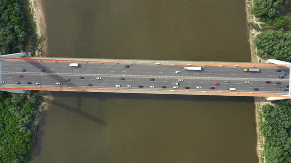 City caring at highway bridge on background smooth river surface drone view alt