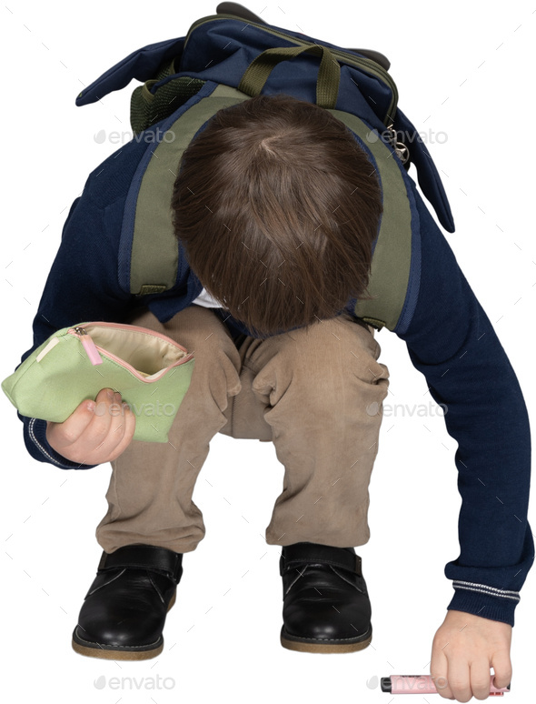 a young boy with a backpack kneeling down with his face in his hands