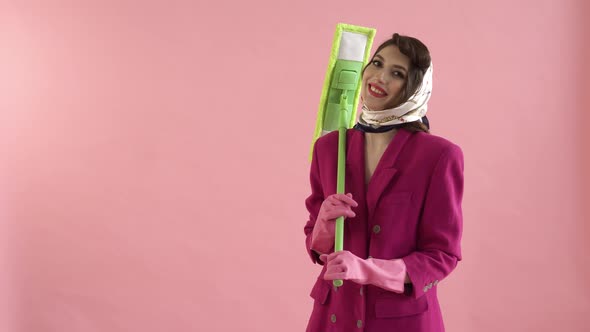 A Young Woman in Rubber Gloves is Holding a Bright Green Mop in Her Hands