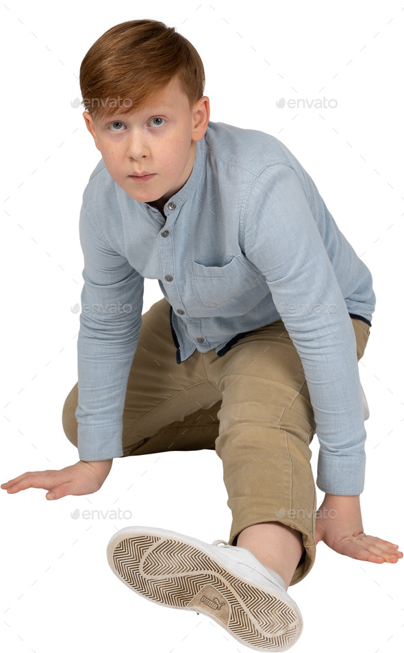 a young boy kneeling down on the floor with his feet