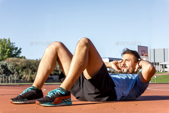 Medium age caucasian man doing abdominal crunches on sunny day
