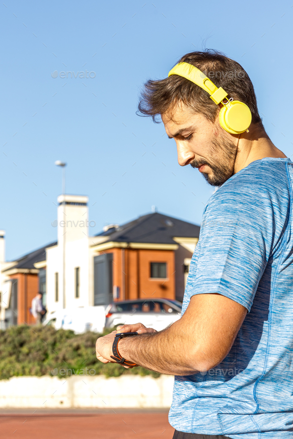 caucasian medium age man using his smart watch before start his workout, outdoors, side view