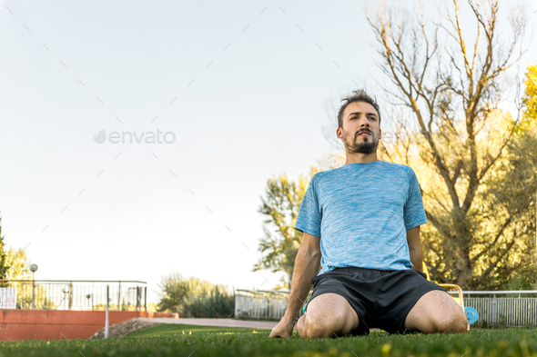 man stretching quadriceps in the park, warming up so as not to get injured