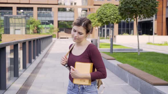 Worried Student with Notebook and Backpack Walks Along Park