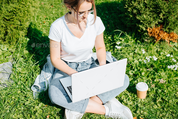 Remote work, freelance, alternative office concept. Young woman freelancer or student with glasses