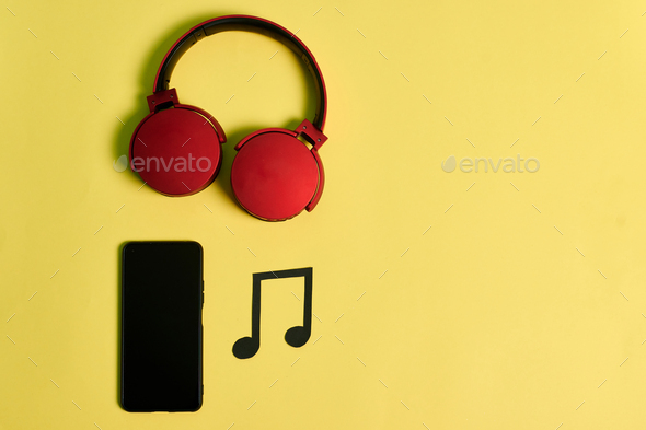Music notes, phone and red headphones on a yellow background