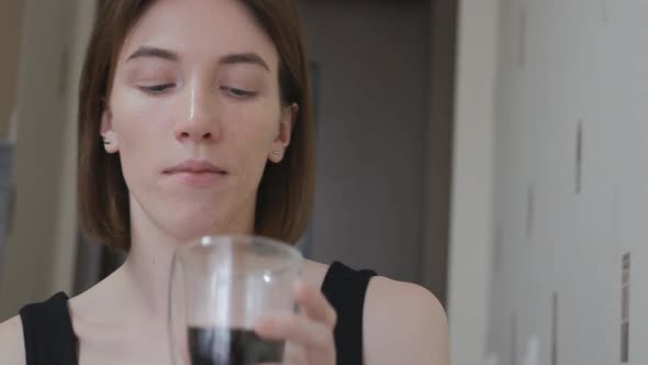 Portrait Cute Young Brownhaired Woman Licks Her Finger After Sweet Eclair and Drinks Black Coffee alt