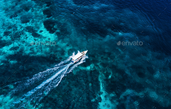 Fast boat at the sea in Bali, Indonesia. Aerial view of floating boat on transparent blue water.