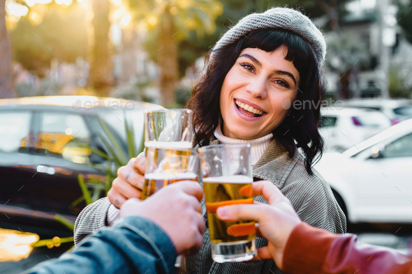 friends clinking glasses of draft beers together toasting at the outdoor kiosk-restaurant