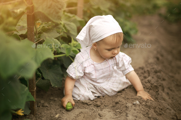 Unwashed dirty girl in a dress crawls in a field and digs in the ground