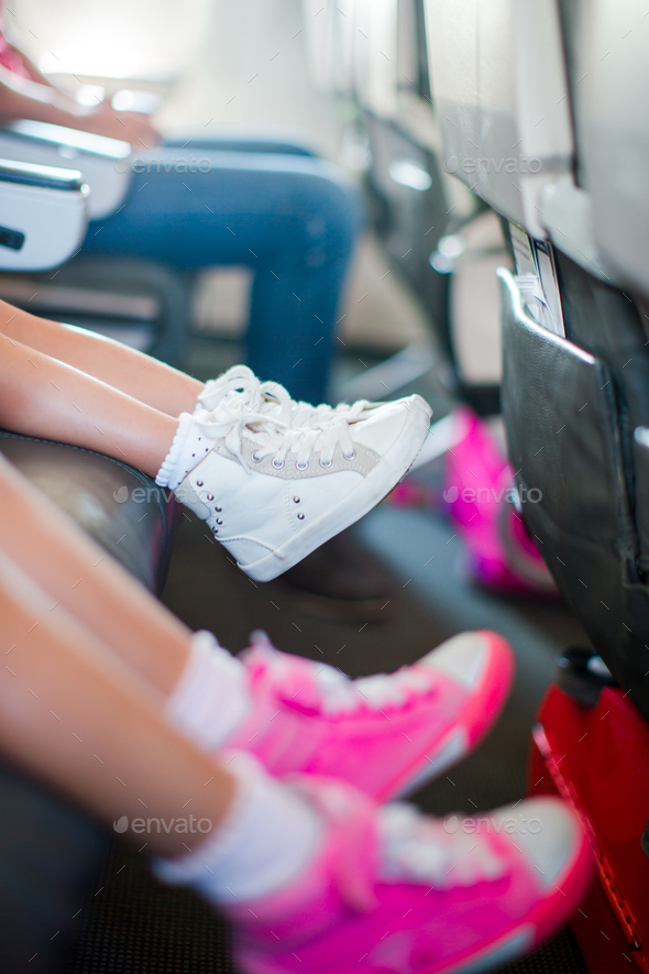 Baby feet in sneakers on seat in the aircraft Little adorable girls walking outdoors in flowers