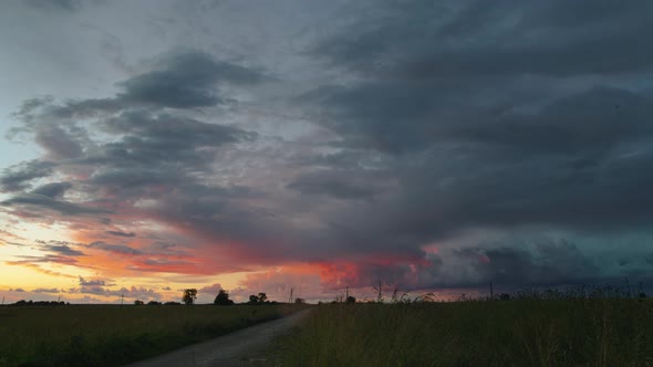 Time lapse of storm clouds floating over field at sunset