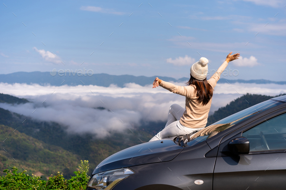 Young woman travelers with car watching a beautiful sea of fog over the mountain