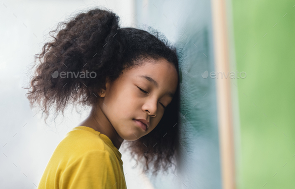 Lazy student african girl bending her head on blackboard while the teacher is beginning to teach