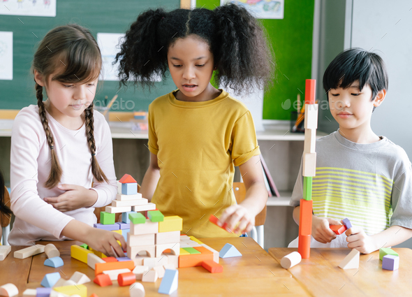 Multi-Cultural Children playing with colorful blocks on table in a ...