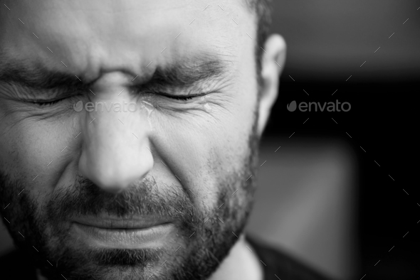 black and white portrait of handsome bearded man crying with closed eyes