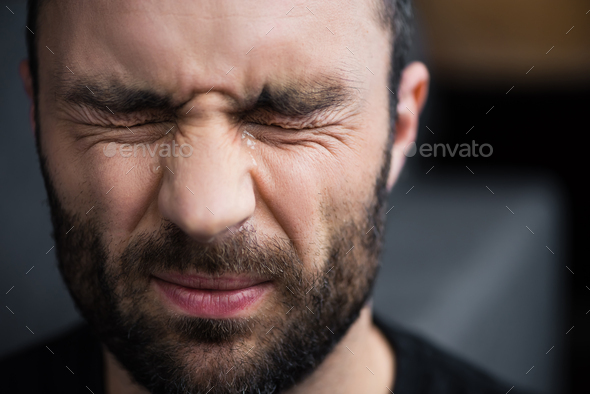 portrait of depressed bearded man crying with closed eyes