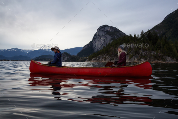 Adventurous people on a canoe are enjoying the Canadian Mountain Landscape