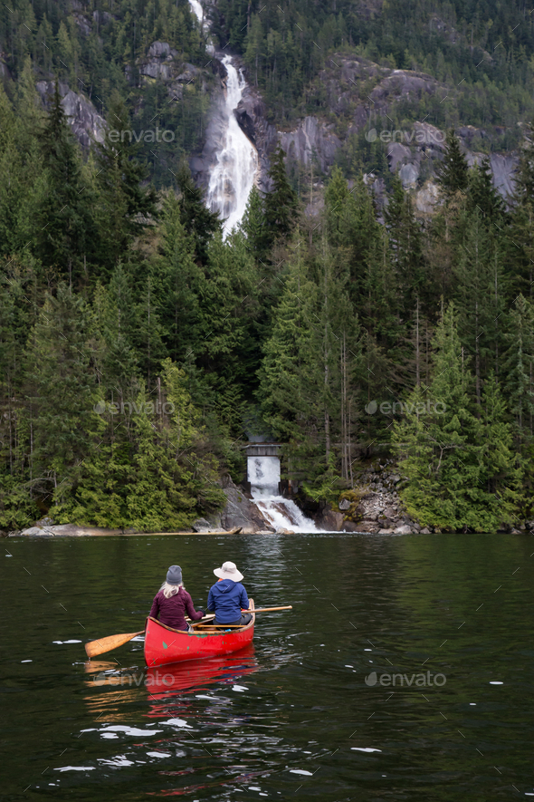 Couple adventurous people on a canoe are enjoying the waterfall