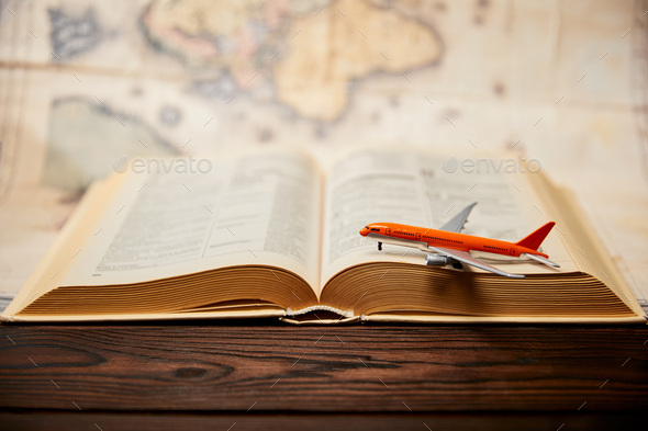 Selective focus of toy plane, book and map on wooden table